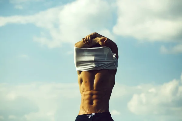 Сексуальна м'язиста людина роздягається на фоні неба — стокове фото