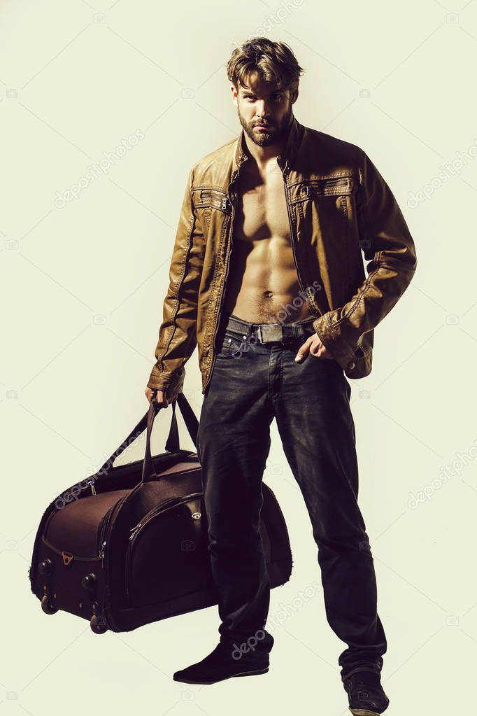muscular bearded man with sexy body holds big bag, suitcase
