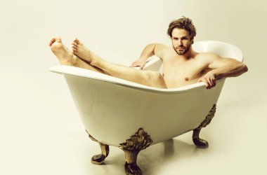 Banyoda çıplak ayakla oturan çıplak yakışıklı