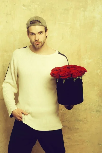 Brodaty mężczyzna trzyma czerwony Róża pole na teksturą ściany — Zdjęcie stockowe