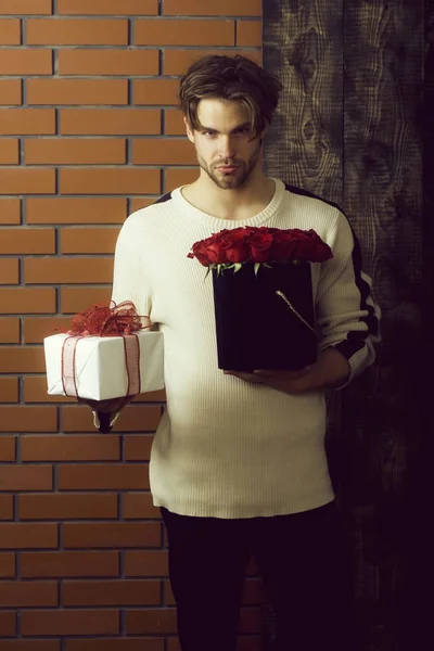 Brodaty mężczyzna trzyma czerwonych kwiatów róży i obecne pole — Zdjęcie stockowe