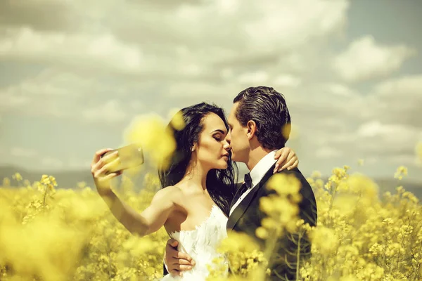 Casamento casal beijo no campo flores amarelas — Fotografia de Stock