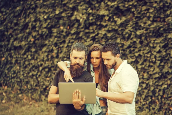 Serious friends use laptop computer