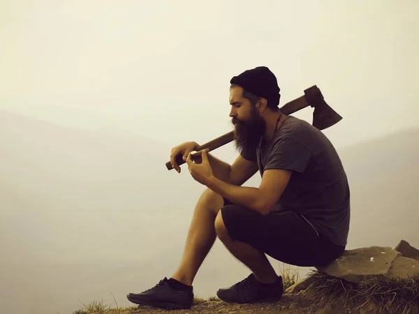 Hombre barbudo con hacha en la montaña — Foto de Stock