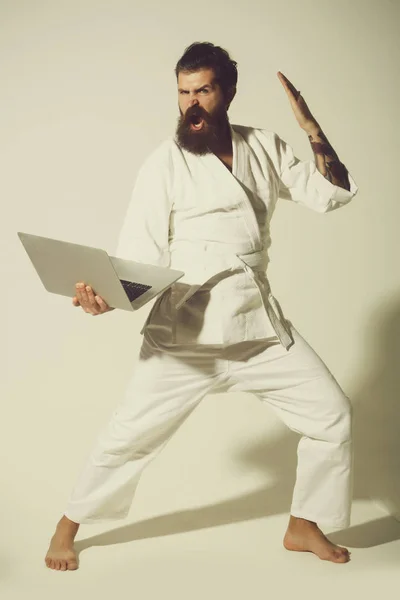 Bearded shouting karate man in kimono with laptop — Stock Photo, Image