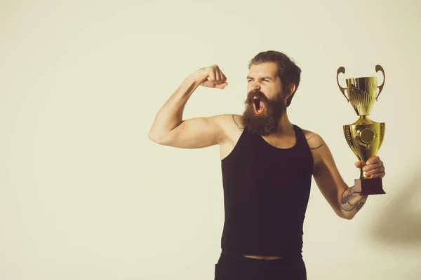 Homem feliz barbudo detém copo campeão de ouro no fundo cinza — Fotografia de Stock