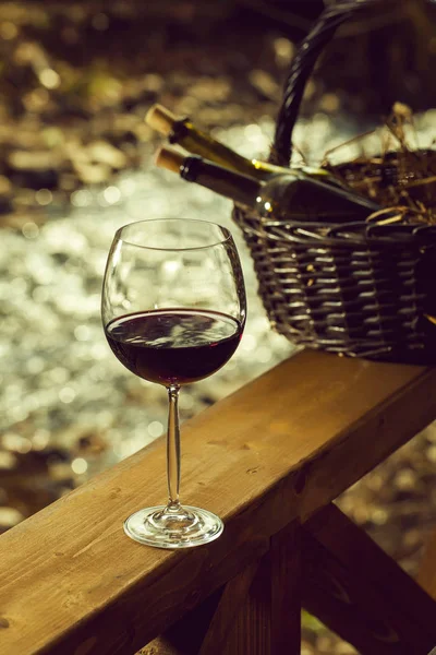 Bicchiere di vino e bottiglie nel cestino — Foto Stock