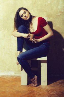 Kahverengi cups ile beyaz ahşap sandalye üzerinde oturan güzel kız