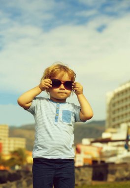 Sarışın saçlı şirin bebek çocuk moda güneş gözlüğü tutar