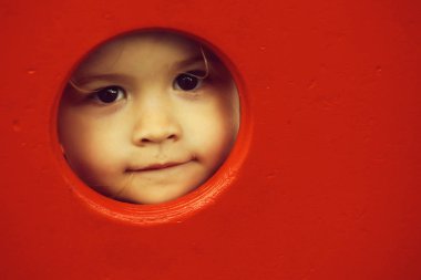 Şirin bebek çocuk yuvarlak kırmızı duvarında delik arar
