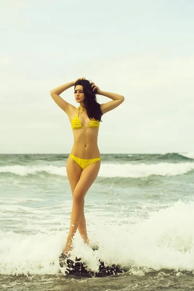 Mooi meisje met sexi gele zwembroek tegoed op rots — Stockfoto
