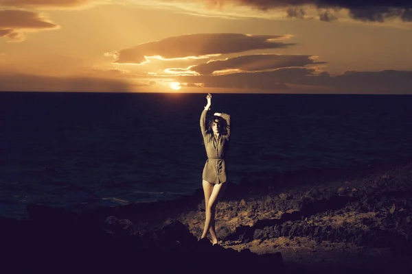 漂亮的女孩在多岩石的海岸海上田园日落期间 — 图库照片