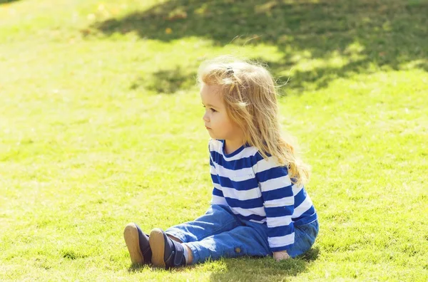 Cute baby szczęśliwy chłopiec siedzi na zielonej trawie w parku — Zdjęcie stockowe