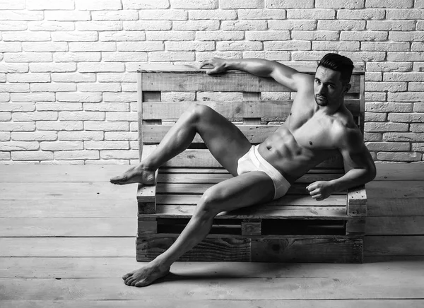 Pohledný svalnatý muž na dřevěné lavici — Stock fotografie