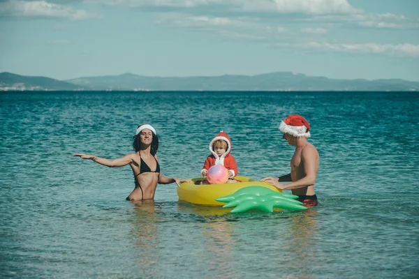 Weihnachtsglückliche Familie auf Ananas-Matratze im Wasser. — Stockfoto