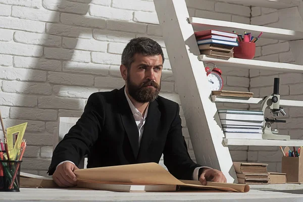 Profesör emin yüz ifadesi ile masa başında oturur