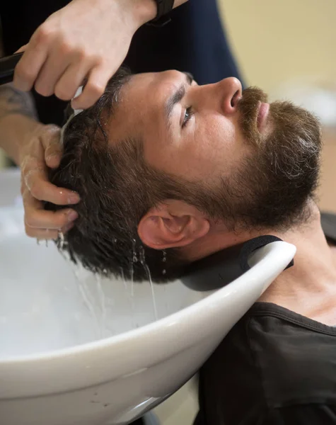 Hipster with serious face in barbershop, new technology.