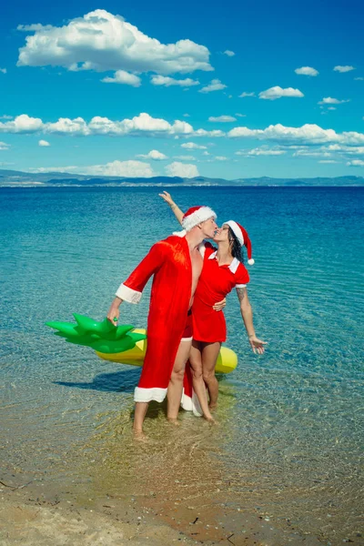 Verliebtes Weihnachtspaar als Weihnachtsmann im Strandwasser — Stockfoto