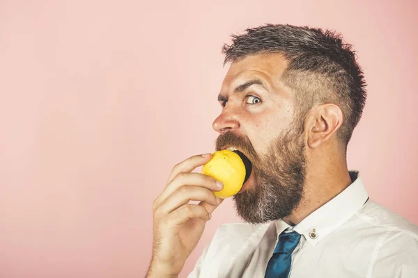 Άνθρωπος με μακριά γένια τρώνε φρούτα λεμόνι σε ροζ φόντο — Φωτογραφία Αρχείου