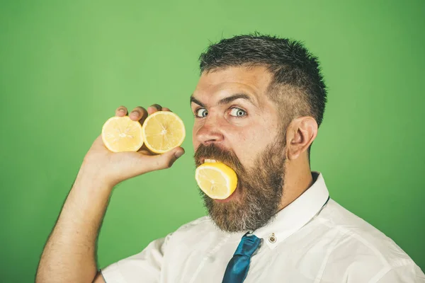 Man med långt skägg äta citron frukt på grön bakgrund — Stockfoto