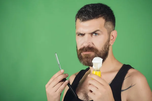 Mies leikkaa parran ja viikset partaveitsellä ja partaharjalla . — kuvapankkivalokuva