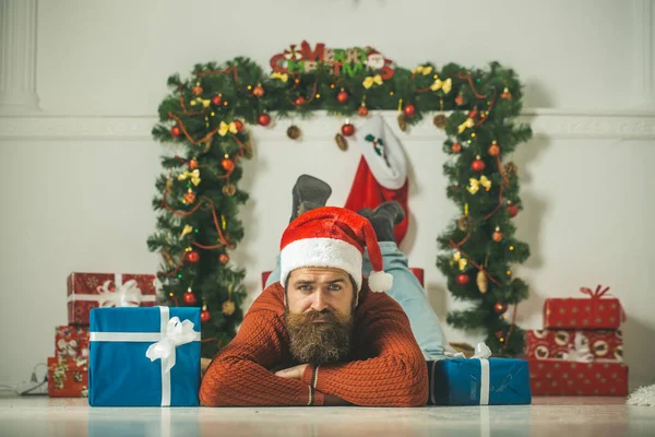 Hombre de Navidad en Santa Sombrero mantenga la caja de regalo en la chimenea —  Fotos de Stock
