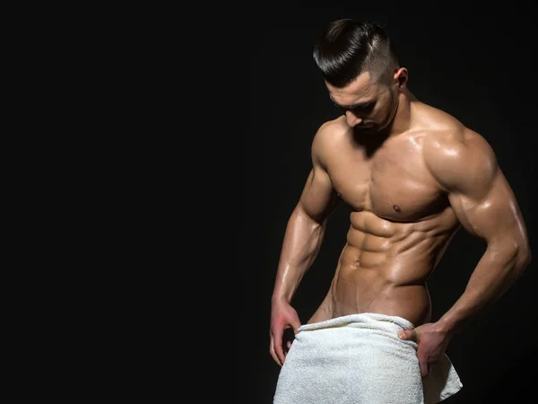 Atletico bodybuilder uomo in asciugamano isolato su sfondo nero . — Foto Stock