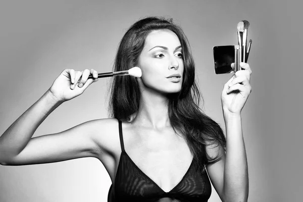 Vrouw in beha met make-up borstel en spiegel — Stockfoto