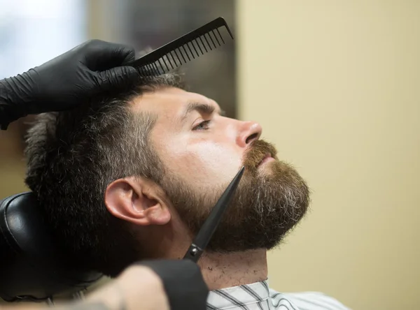 Man cut long beard and mustache with scissors.