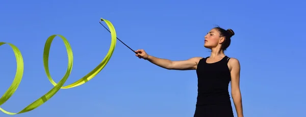 Mujer gimnasta en ropa deportiva negra con cinta verde . — Foto de Stock