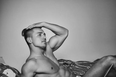 Dizüstü bilgisayar ile yatakta seksi adam