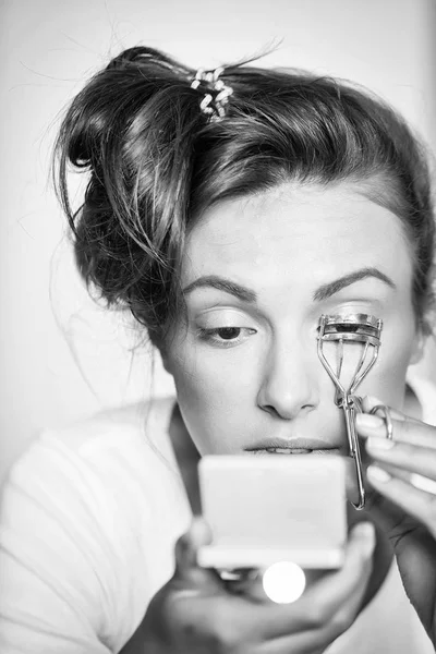 Pretty girl curling eyelashes with tongs — Stock Photo, Image
