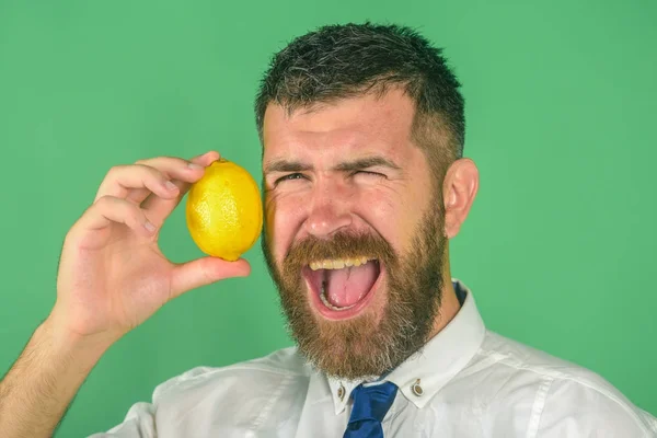 Ευτυχισμένος άνθρωπος με γένια τρώνε φρούτα λεμόνι σε πράσινο φόντο — Φωτογραφία Αρχείου