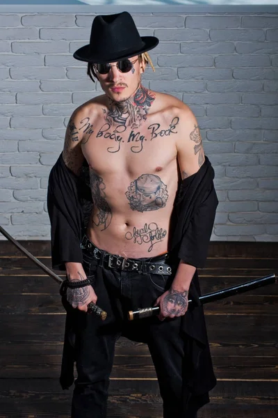 Savaşçı siyah şapka ve dövmeli gövde gösterilen açık giyim