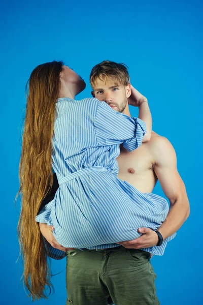 Мужчина держит женщину в руках на синем фоне — стоковое фото