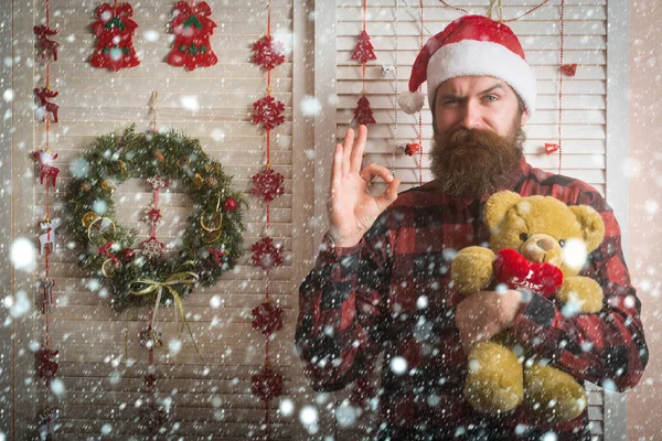 Homem de natal com barba no rosto sorridente segurar urso presente — Fotografia de Stock