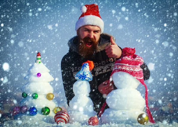 Babbo Natale uomo mettere cappello sul pupazzo di neve e mostrando gesto ok — Foto Stock