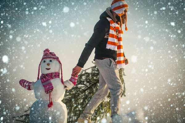 Chico y escultura de nieve con sombreros y bufandas — Foto de Stock