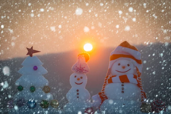 Χιονάνθρωποι με χαμογελαστά πρόσωπα σε καπέλα για βραδινό τοπίο — Φωτογραφία Αρχείου