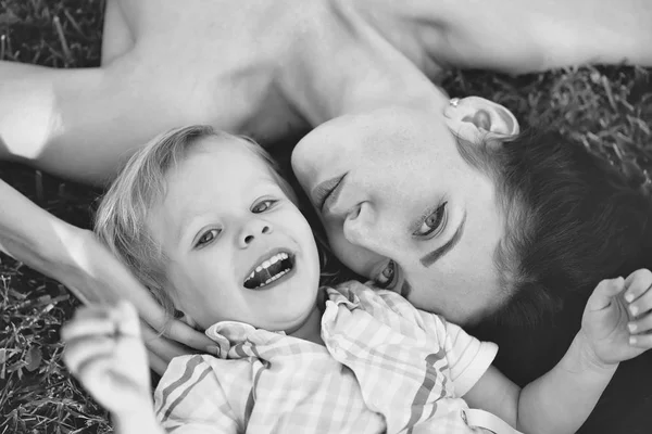 Uśmiechający się ładny chłopiec i Ładna matka leżącego na zielonej trawie — Zdjęcie stockowe