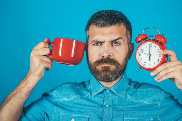 Hombre con barba en cara triste con taza, despertador — Foto de Stock