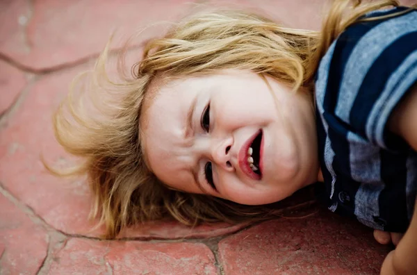 Niño con el pelo largo y rubio llorar en baldosas marrones —  Fotos de Stock