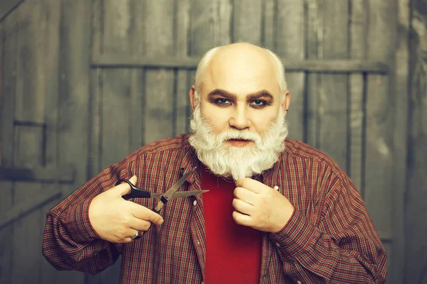 old man cutting beard with scissors