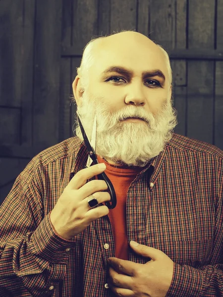 old man cutting beard with scissors