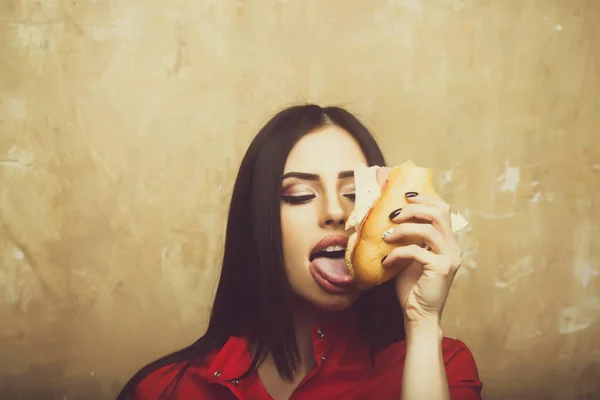 Hungry sexy pretty brunette woman eats big sandwich or burger — Stock Photo, Image