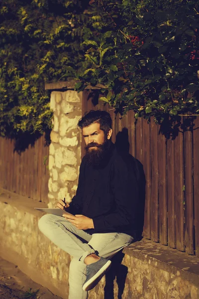 Бородатый мужчина на улице с карандашом и запиской — стоковое фото