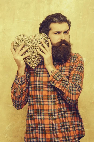 bearded man with long beard holds wicker heart