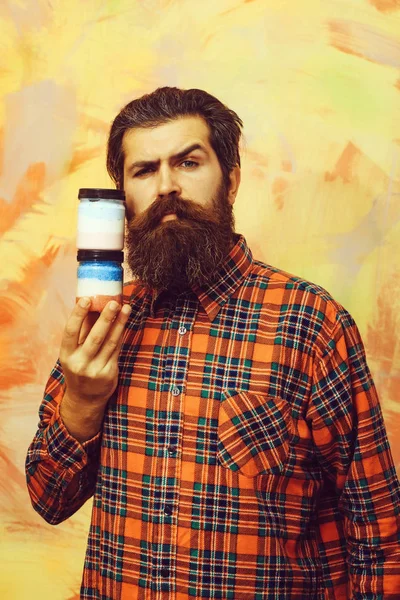 Серьезный бородатый мужчина с двумя косметическими банками — стоковое фото