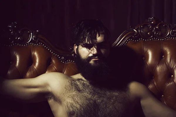 Bearded naked man on couch