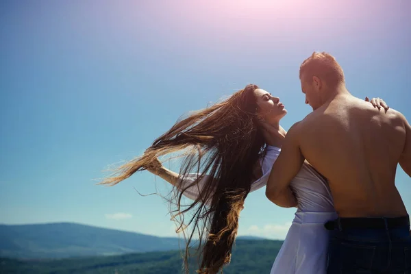 Uomo abbraccio donna con i capelli lunghi volanti nella giornata di sole — Foto Stock